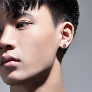 Vintage silver sunburst stud earring with retro metallic texture worn by a male model