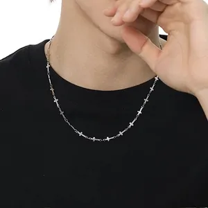 Primo piano di una collana con ciondolo a croce in argento su una t-shirt nera da uomo