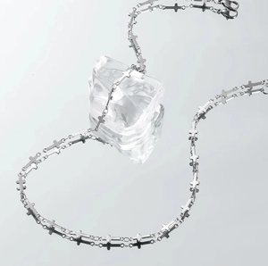 Collana a catena con croce d'argento su un blocco di ghiaccio con riflesso a specchio