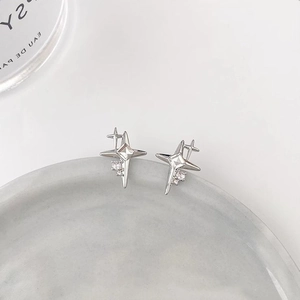 Minimalist silver star stud earrings with central crystal stone on light grey background