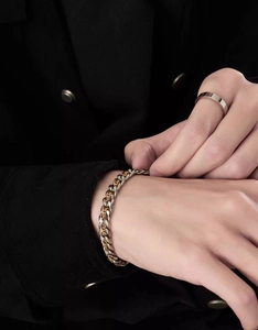 Detail of two-tone gold and silver Cuban link bracelet on wrist with a minimal silver ring