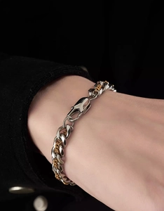 Detail of silver Cuban chain and gold twist rope bracelet with branded lobster clasp