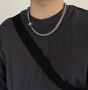 Gros plan sur collier industriel argenté à deux rangs avec pendentif étoile à 4 branches