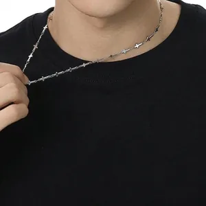 Collana con piccoli ciondoli a croce in argento indossata su una maglietta nera casual