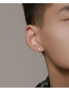 Close-up of a minimalist silver stud earring worn by a male model with a sleek matte finish