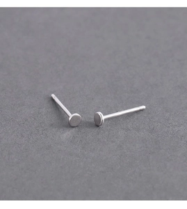 Detail of minimalist silver round stud earrings on dark textured card for men