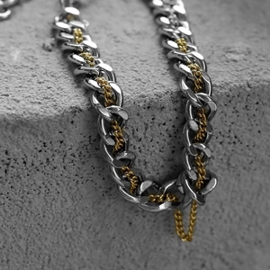 Detailed close-up of dual-tone silver and gold Cuban link chain with industrial texture