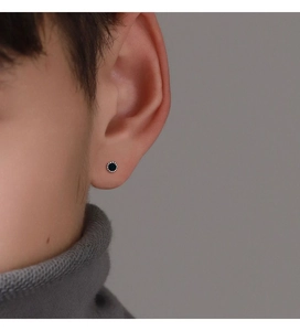 Close-up of minimalist silver stud earring with black inlay and beaded edge on model ear