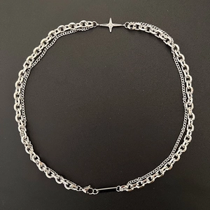 Gros plan sur le collier à double chaîne argentée avec pendentif rectangulaire noir sur fond noir