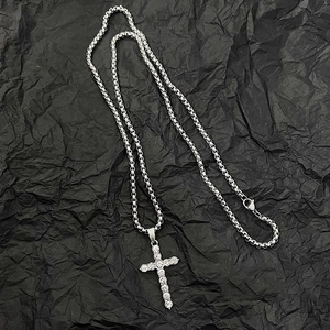 Detail of silver iced-out cross pendant necklace with round zircons on black background