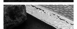 Detailansicht der silbernen Metallperle mit Wabenstruktur auf vulkanischem Gestein