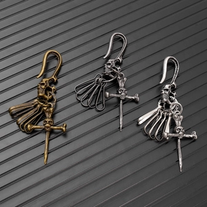 Gothic skull keychains in bronze, silver, and black metal on industrial background