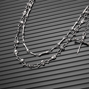 Close-up of gothic silver skull and bone links metal chain with cross pendant accessory