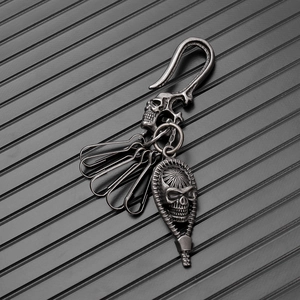 Detail of vintage silver skull keychain with punk hook and engraved metal charms