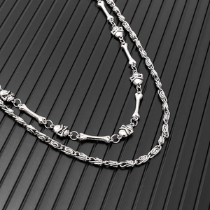 Macro detail of punk double-layer silver chain with skull pendants and bone links