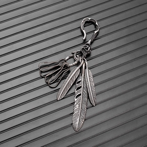 Macro detail of retro skull S-hook and silver feather charms on vintage keychain