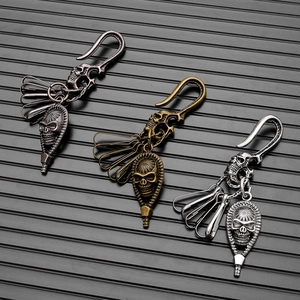 Three vintage skull keychains in bronze, brass and silver on a black textured background