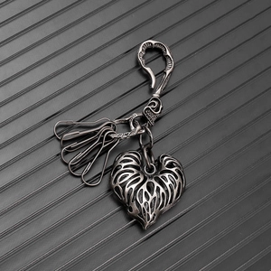 Detail of vintage heart leaf metal keychain with carabiner on dark textured surface