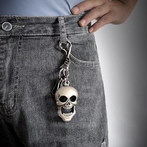 Detail of vintage punk skull keychain accessory hanging on dark grey denim jeans
