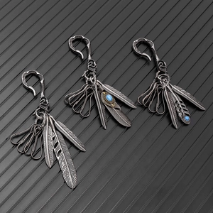 Vintage silver feather keychains with turquoise inlays on a black metallic background
