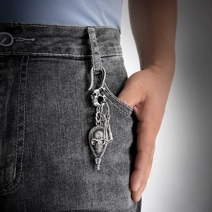 Detail of vintage skull keychain pendant on denim, showing antique silver metal finish