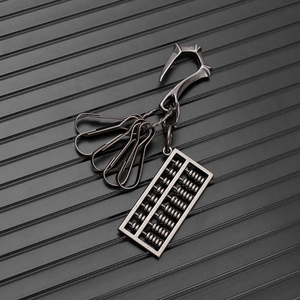Macro detail of retro metal abacus pendant and industrial snap hooks on a denim keychain