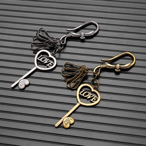 Detail of vintage heart keys with LOVE engraving and eagle lobster clasp on black background