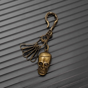 Macro view of vintage bronze skull keychain with utility hooks on textured background