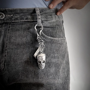 Retro silver metal skull keychain and pendant on vintage grey denim jeans for hip-hop style