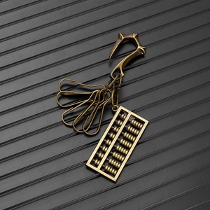 Detail of vintage brass keychain featuring a mini abacus pendant and metal paperclip hooks