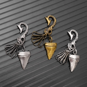 Detail view of vintage shark tooth and fishhook keychains in antique silver, bronze and chrome