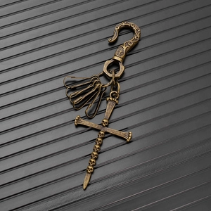 Detail of vintage gothic brass keychain with skull cross pendant and S-hook on dark background