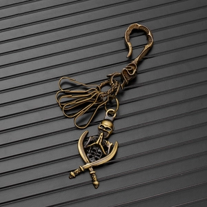 Detail of vintage bronze skull keychain with praying hands and crossed swords design