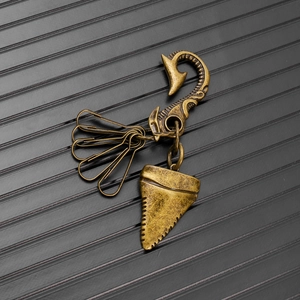 Detail of vintage bronze shark tooth pendant and fish hook keychain with punk styling