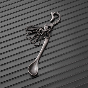 Macro view of vintage silver alloy spoon pendant and Maori fish hook clip on a key chain