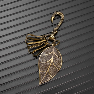 Detail view of vintage brass fishhook keychain with engraved leaf pendant and metal rings