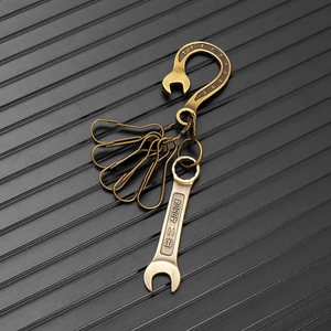 Macro detail of bronze wrench pendant keychain with engraved B=40504 serial on grey texture