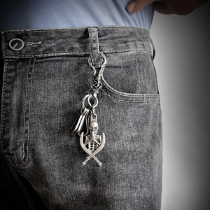 Detail of silver skull and cross-swords pendant hanging on grey denim jeans waist