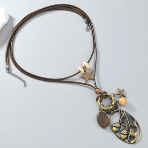 Détail d'un collier bohème avec pendentif feuille en bronze, étoiles et perles en bois