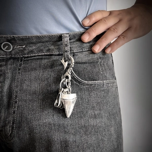 Retro shark tooth keychain accessory hanging on grey denim jeans for men