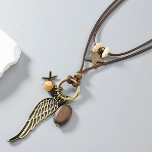 Close-up of vintage bronze feather pendant with star charm and wooden bead on woven cord