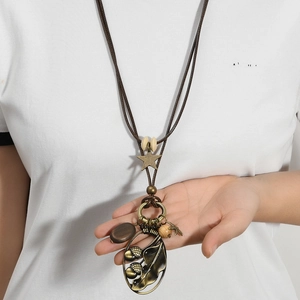 Long collier vintage avec pendentif feuille en bronze et perles sur cordon tressé