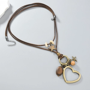Gros plan du pendentif cœur et étoile sur un long collier bohème en cordon tressé