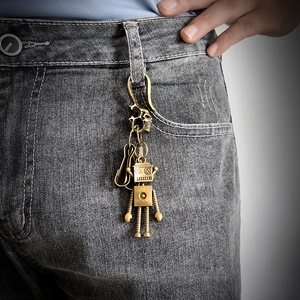 Detail of vintage brass robot pendant with skull clip attached to denim belt loop
