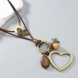 Détail du collier long à cœur avec breloques en bronze et perles en bois sur cordon brun