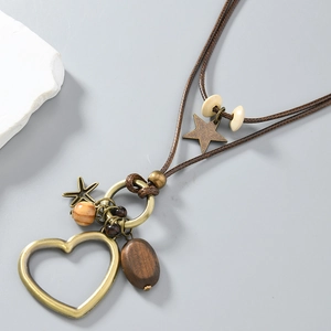 Détail d'un pendentif cœur en bronze avec perle en bois sur collier long en cordon ciré