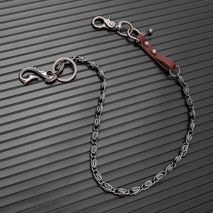 Detail of vintage silver metal wallet chain with leather strap on black textured background