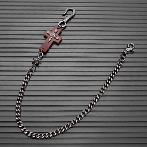 Detail of gothic silver chain with brown leather cross and metal skull punk elements