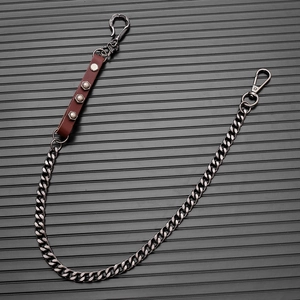 Detail of punk trousers chain with dark brown leather and metal studs on gunmetal link