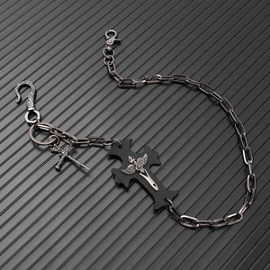 Detail of punk metal trouser chain featuring a black cross pendant and skull charm